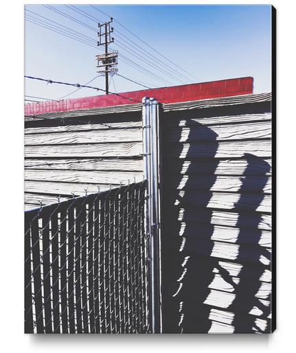 steel fence and wooden fence with red building and blue sky background in the city Canvas Print by Timmy333