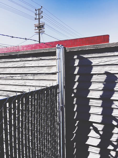 steel fence and wooden fence with red building and blue sky background in the city by Timmy333